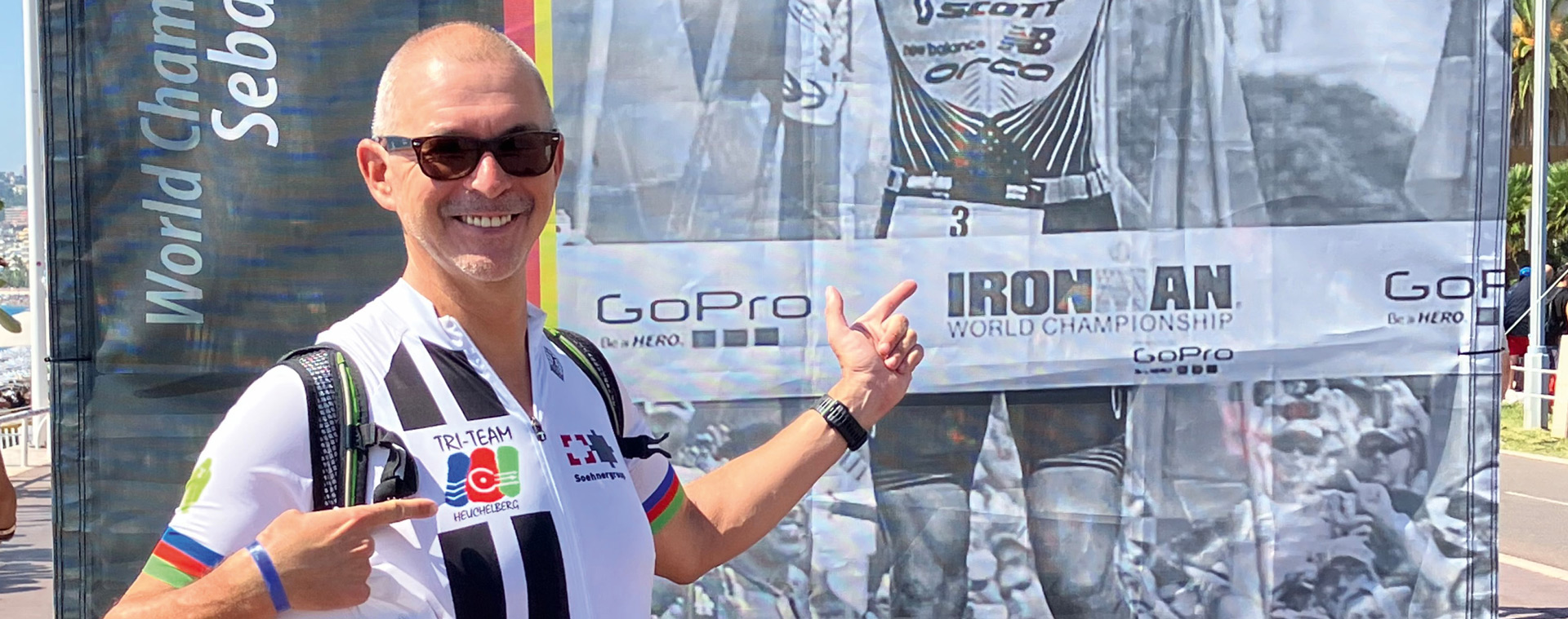 Triathlet Albrecht Trölsch beim Ironman World Championship in Heidelberg Triathlet Albrecht Trölsch in TRI-TEAM Trikot posiert vor Ironman World Championship Banner